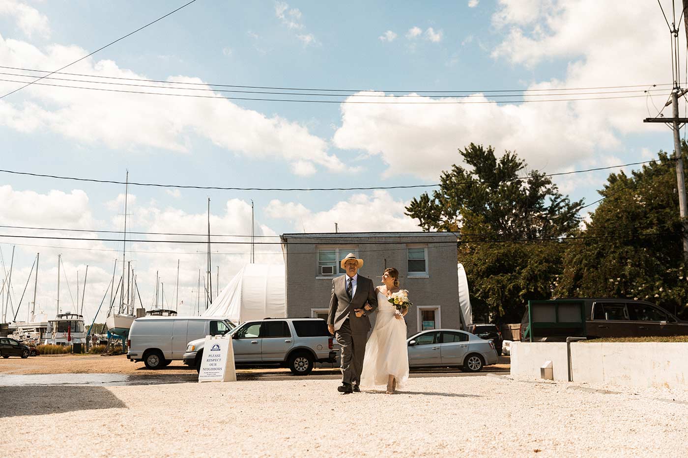 bride and father walkiing through gravel lot
