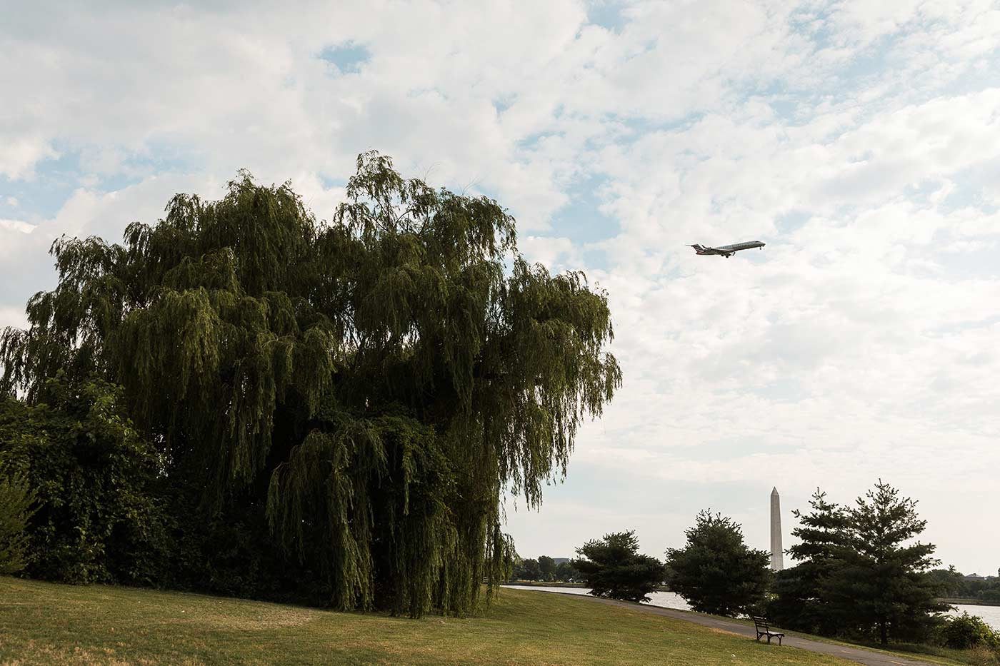 airplane flying over the potomac river with the washington monument in the background