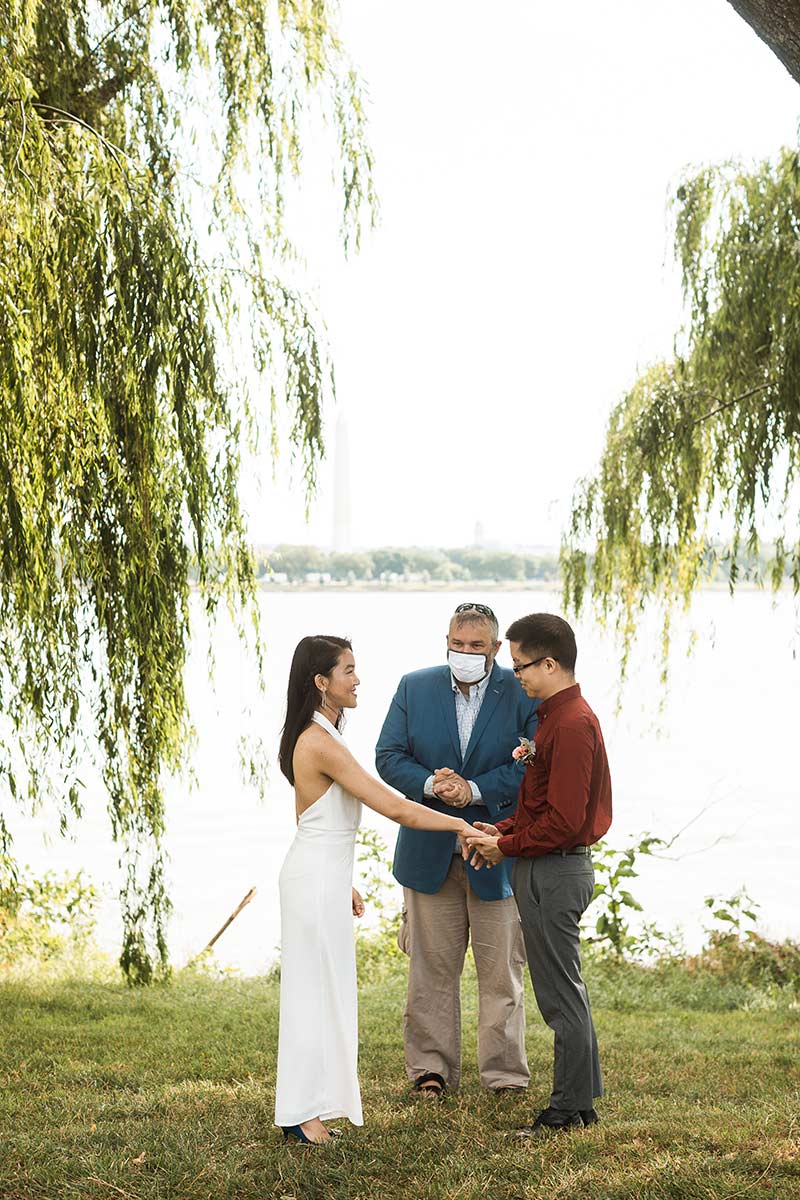 Bride and groom holding hands with officiant behind them. 