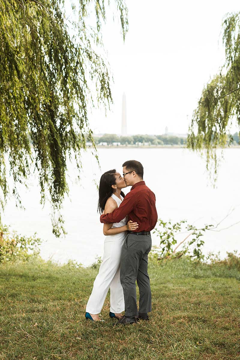 Couple kissing with washington monument in background. 