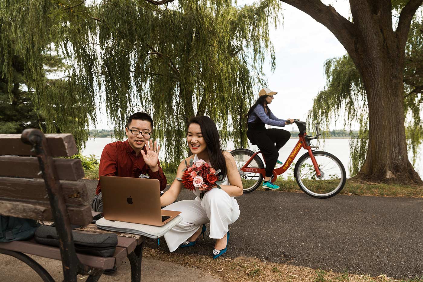 Bride and groom on laptop, woman riding bike in background