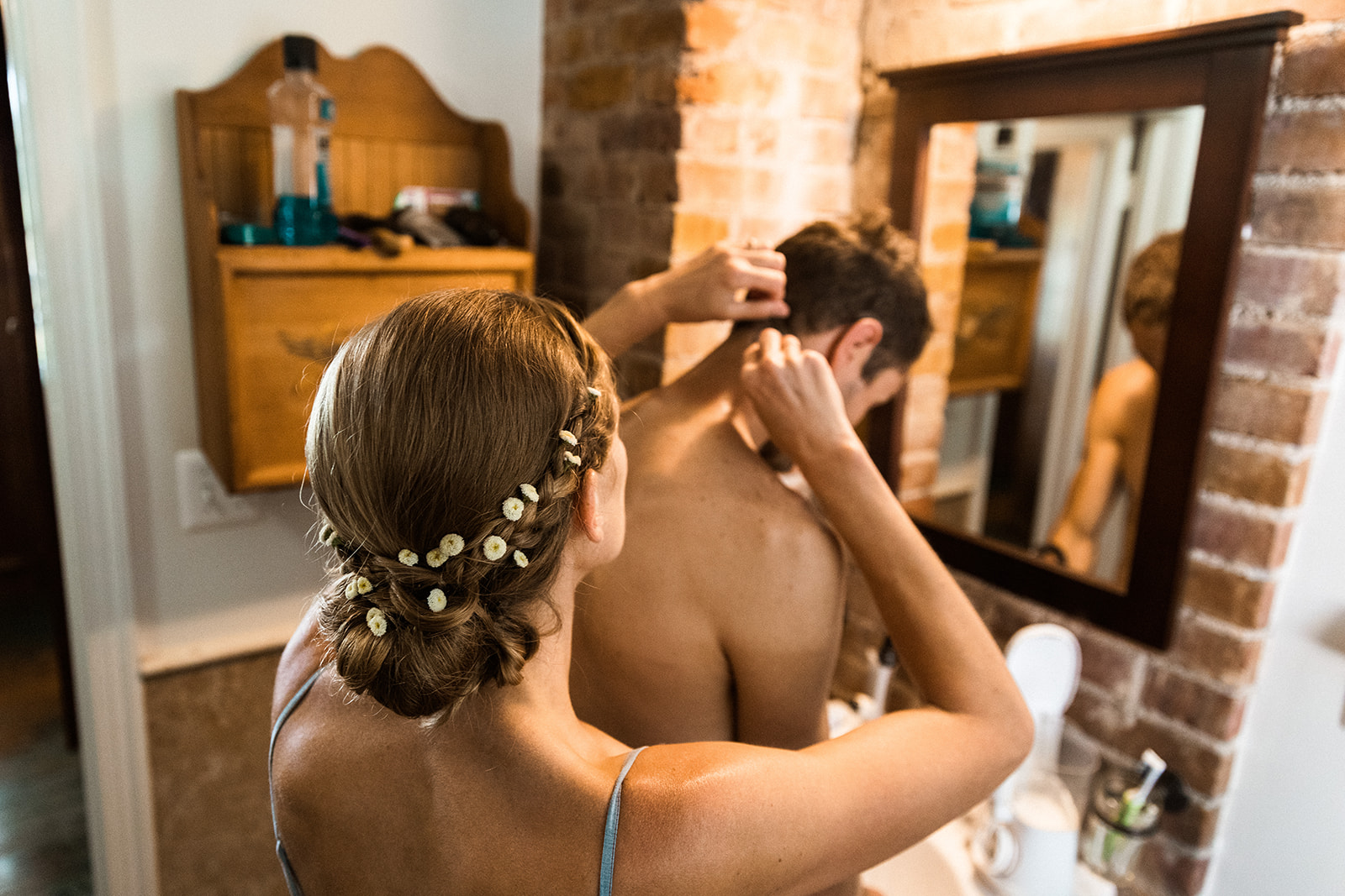 Bride helping groom style hair on wedding day
