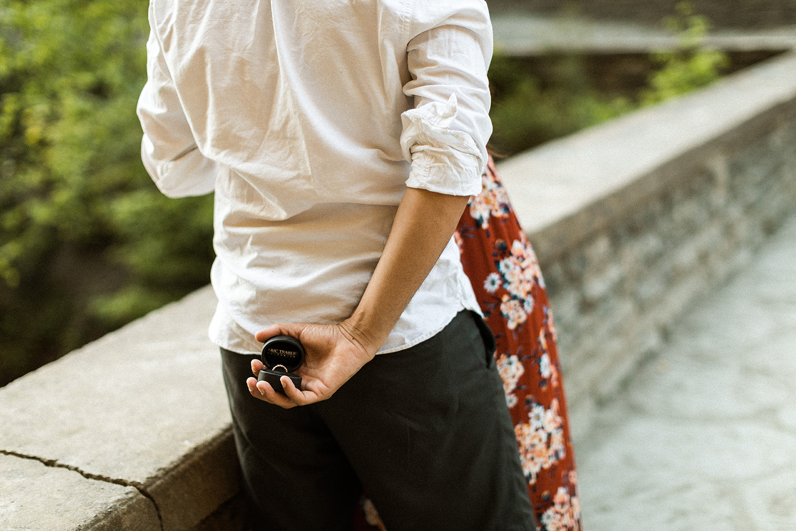 man holding ring box with engagement ring behind his back