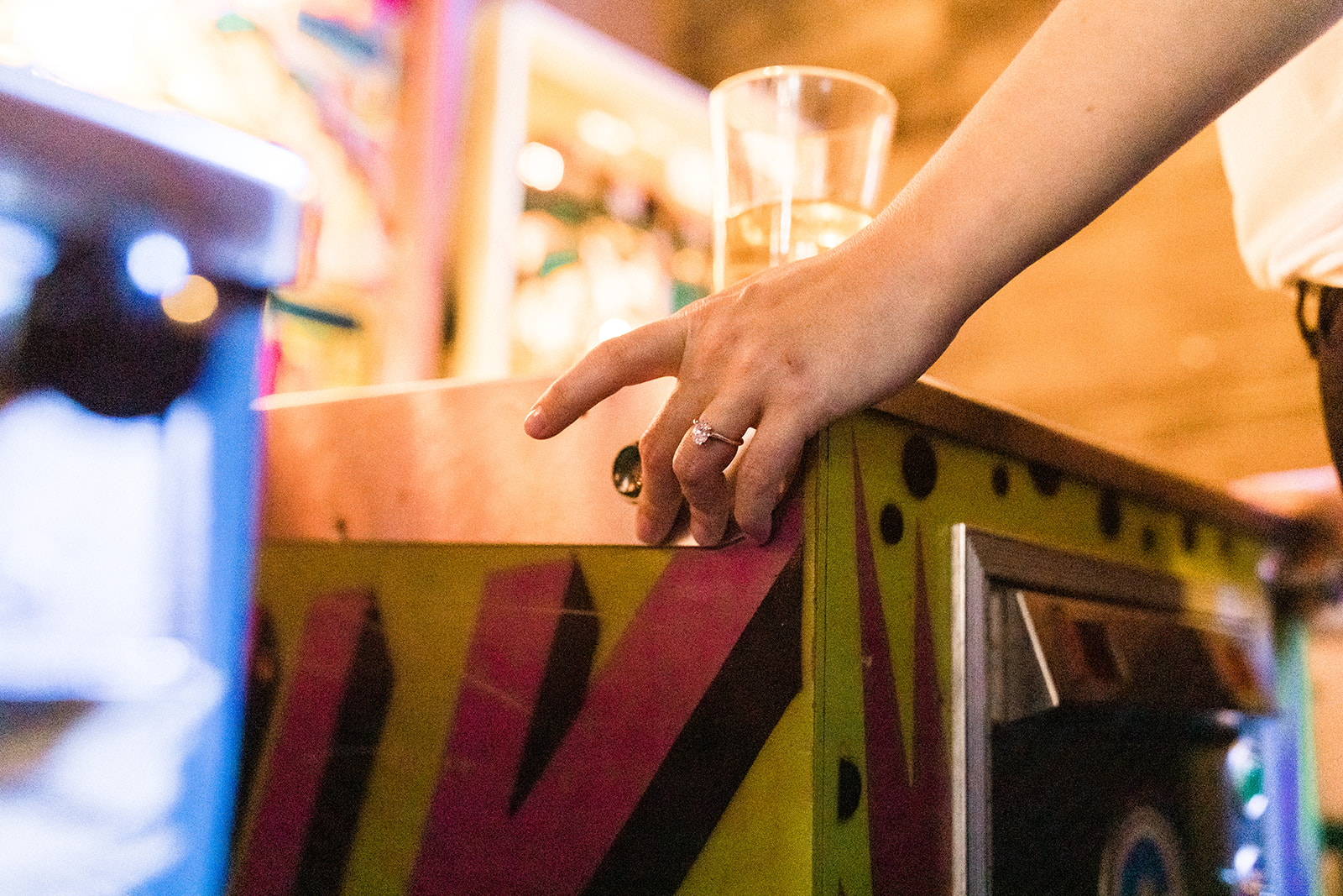Woman wearing engagement ring playing pinball