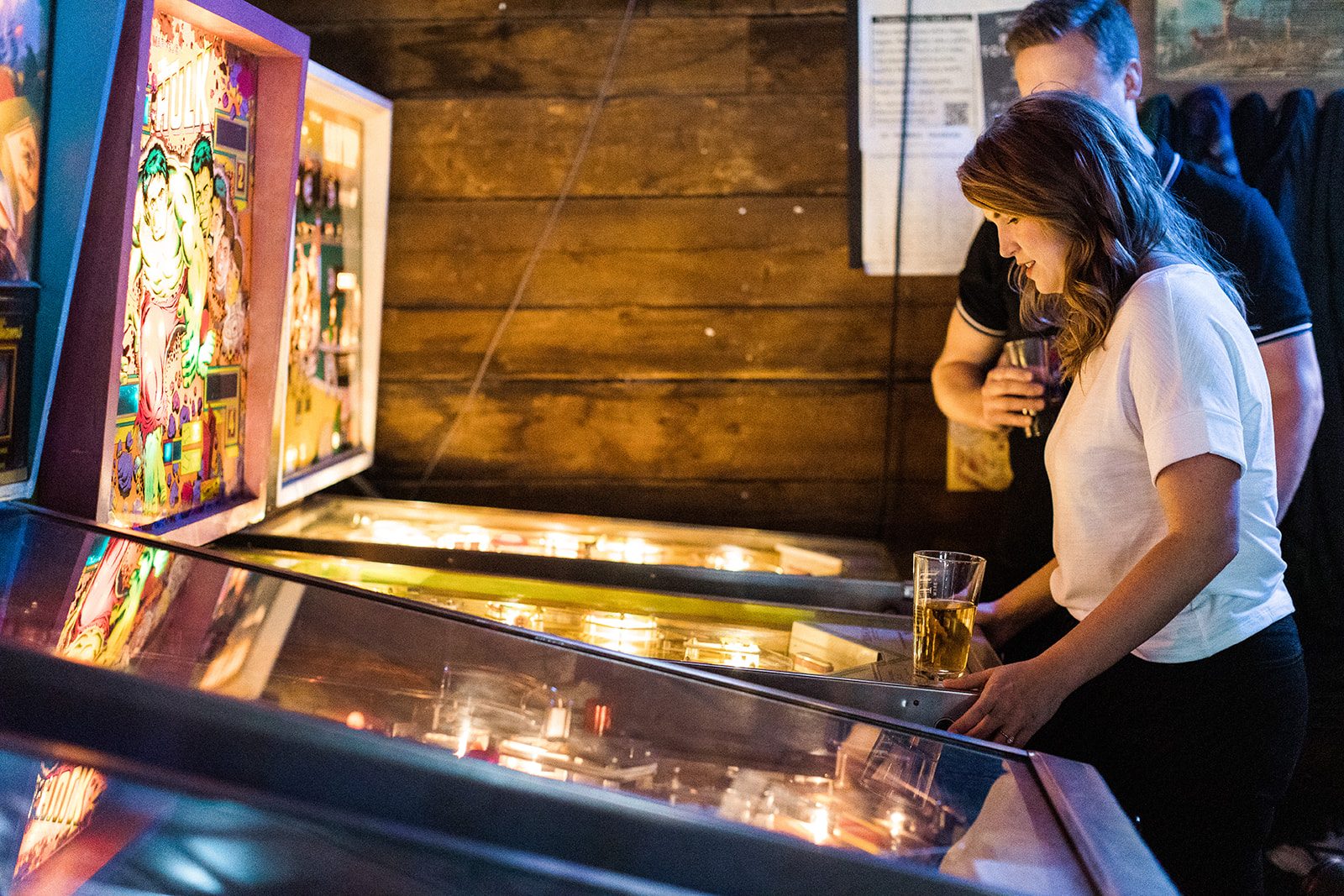 woman playing pinball while man watches