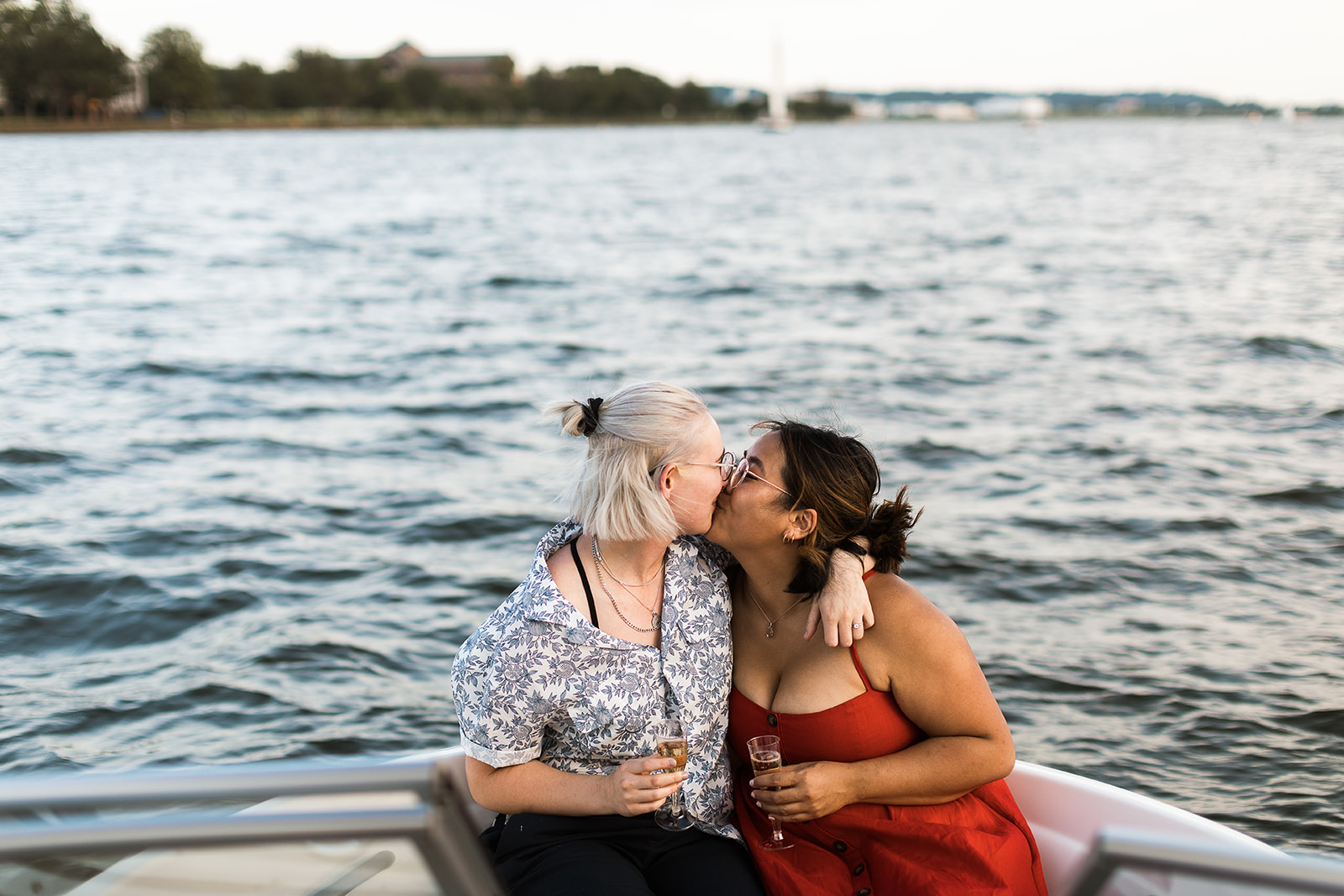 two women kissing and holding champagne on a boat