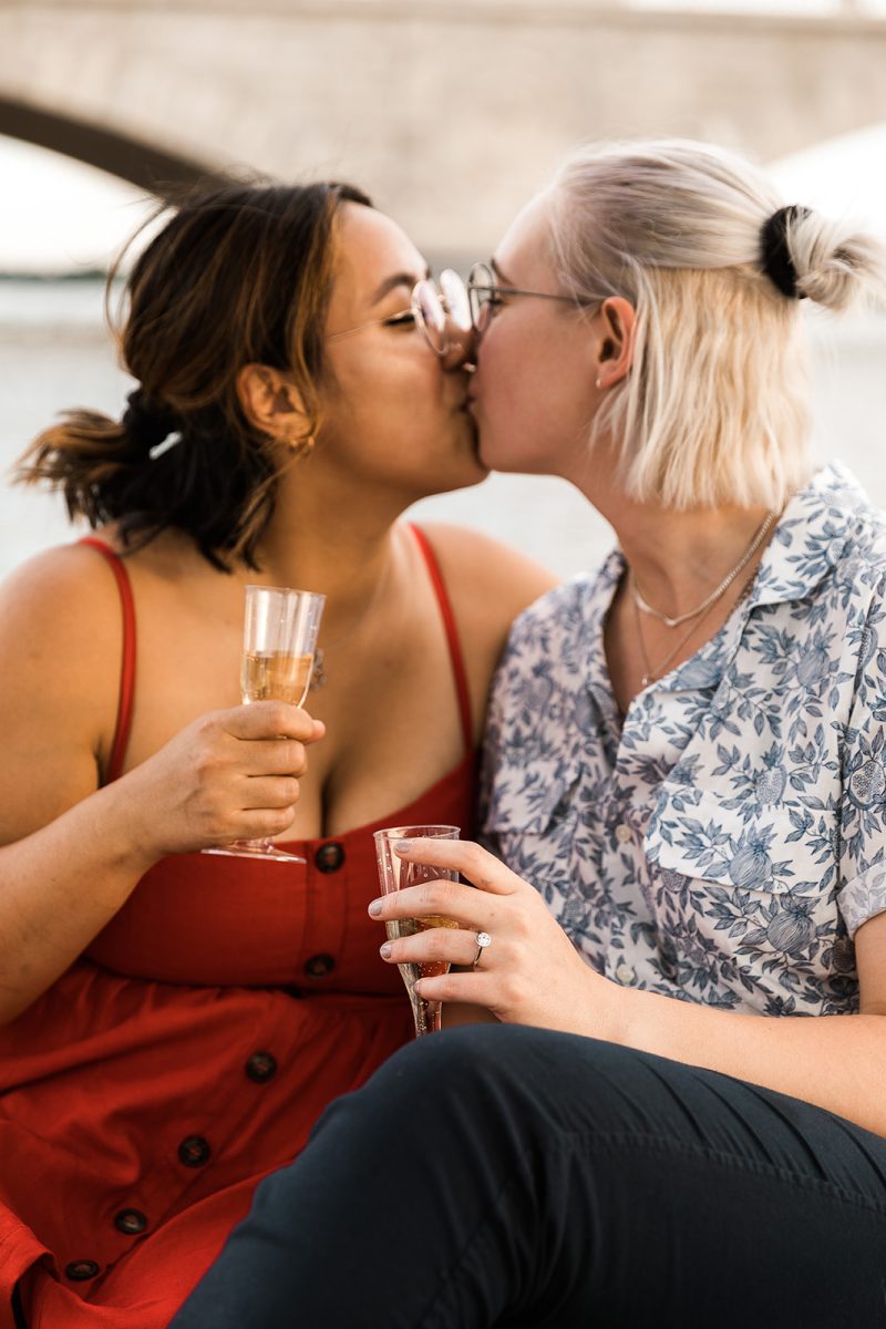 two women kissing and showing off engagement ring