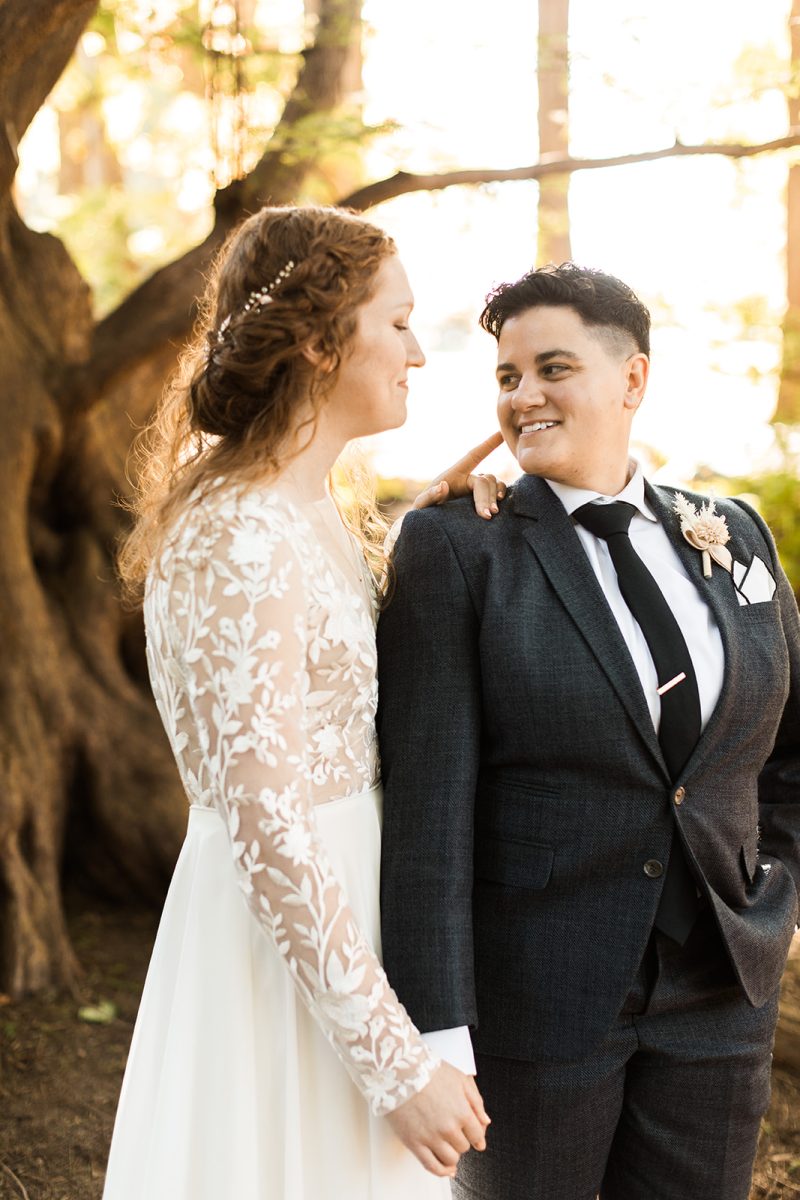 Lesbian couple on their wedding day looking at each other and smiling. 