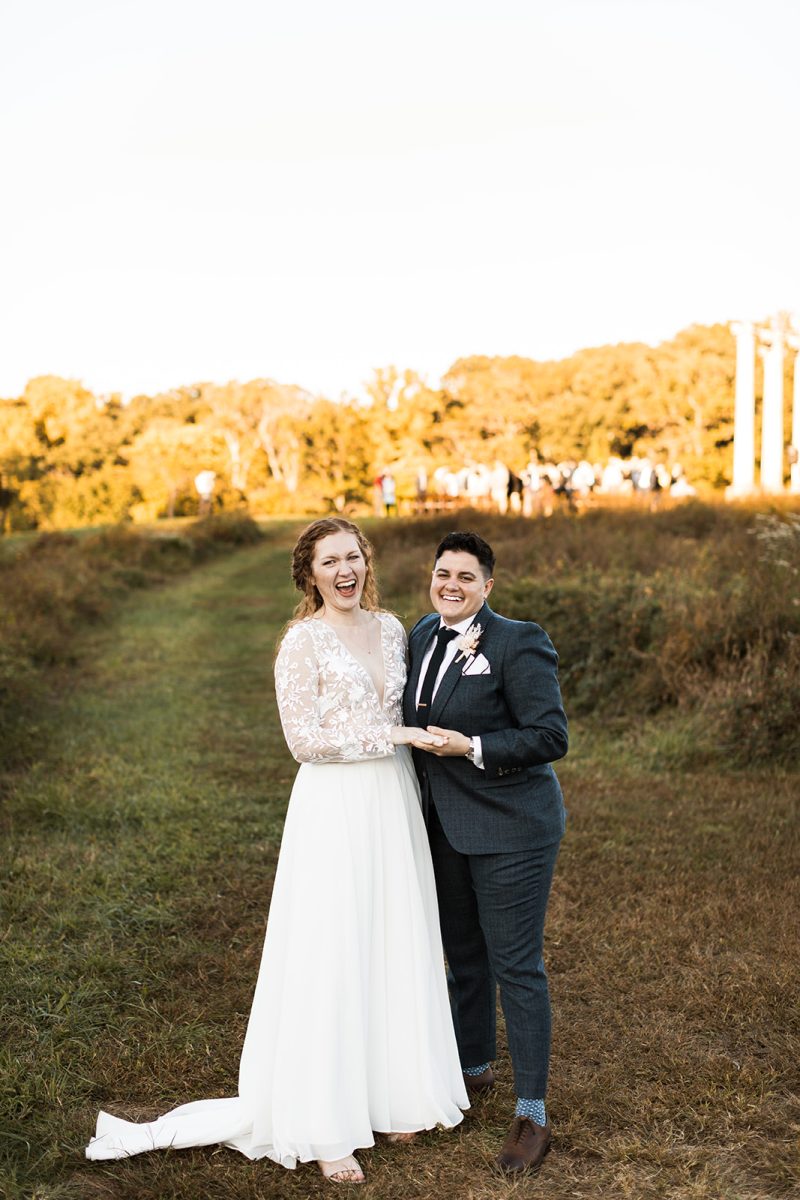 LGBTQ+ couple laughing adn holding hands on wedding day. 