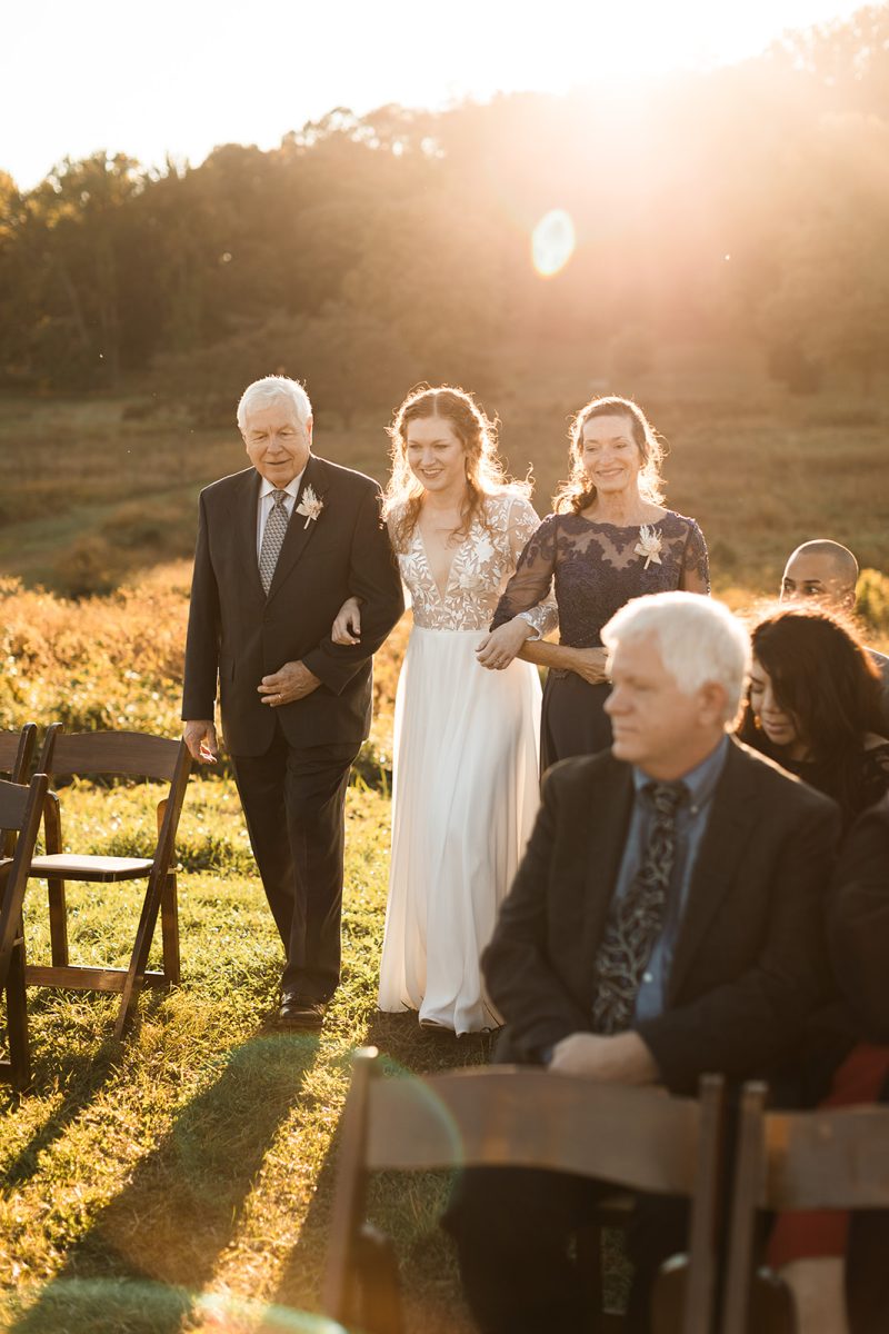 Bride walking down aisle with both mom and dad. 
