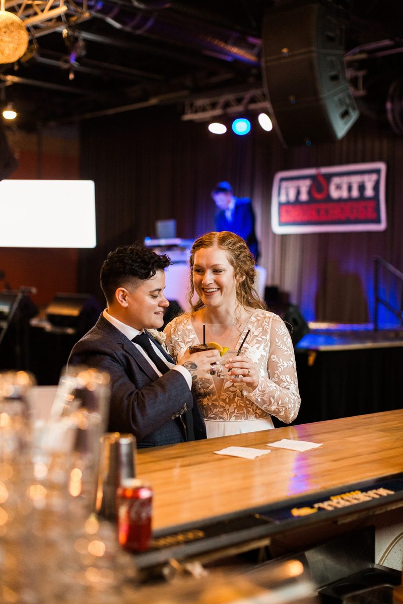 Couple in wedding attire cheersing drinks at the bar at Ivy City Smokehouse. 
