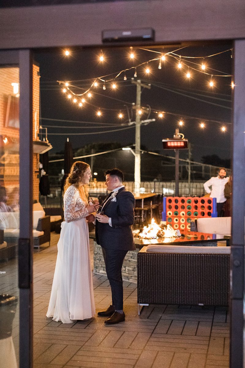 Couple in wedding attire standing on patio next to fire pit at Ivy City Smokehouse in Washington, DC. 
