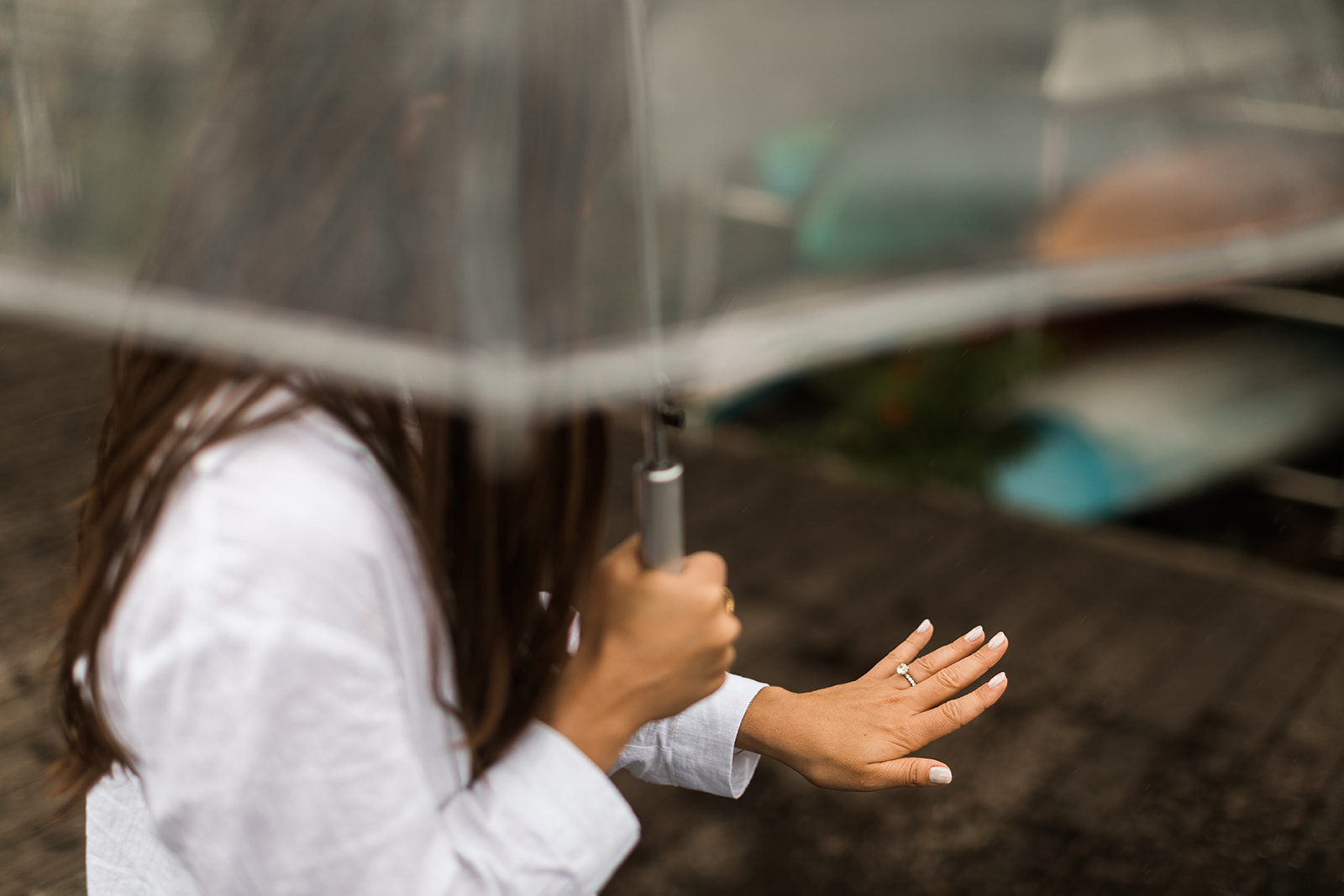 woman holding umbrella admiring her engagement ring
