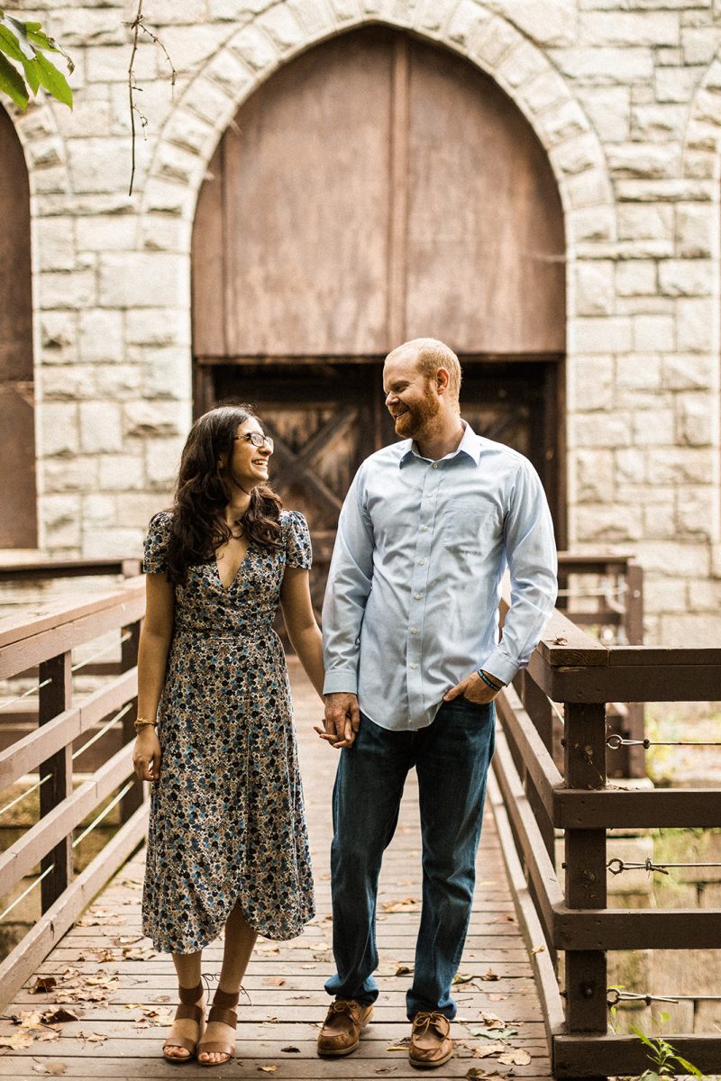 couple holding hands and walking across bridge at james river pump house