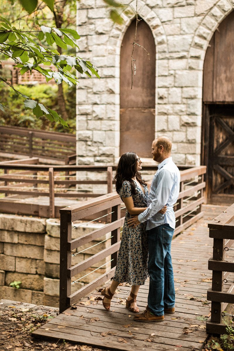 couple embracing standing on wooden bridge at james river pump house