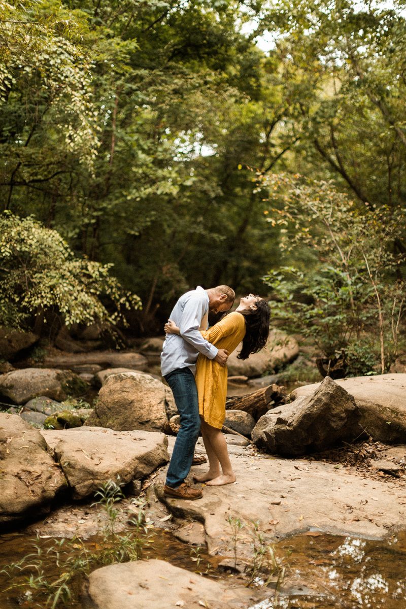 couple laughing and standing on rocks next to the james river near richmond virginia