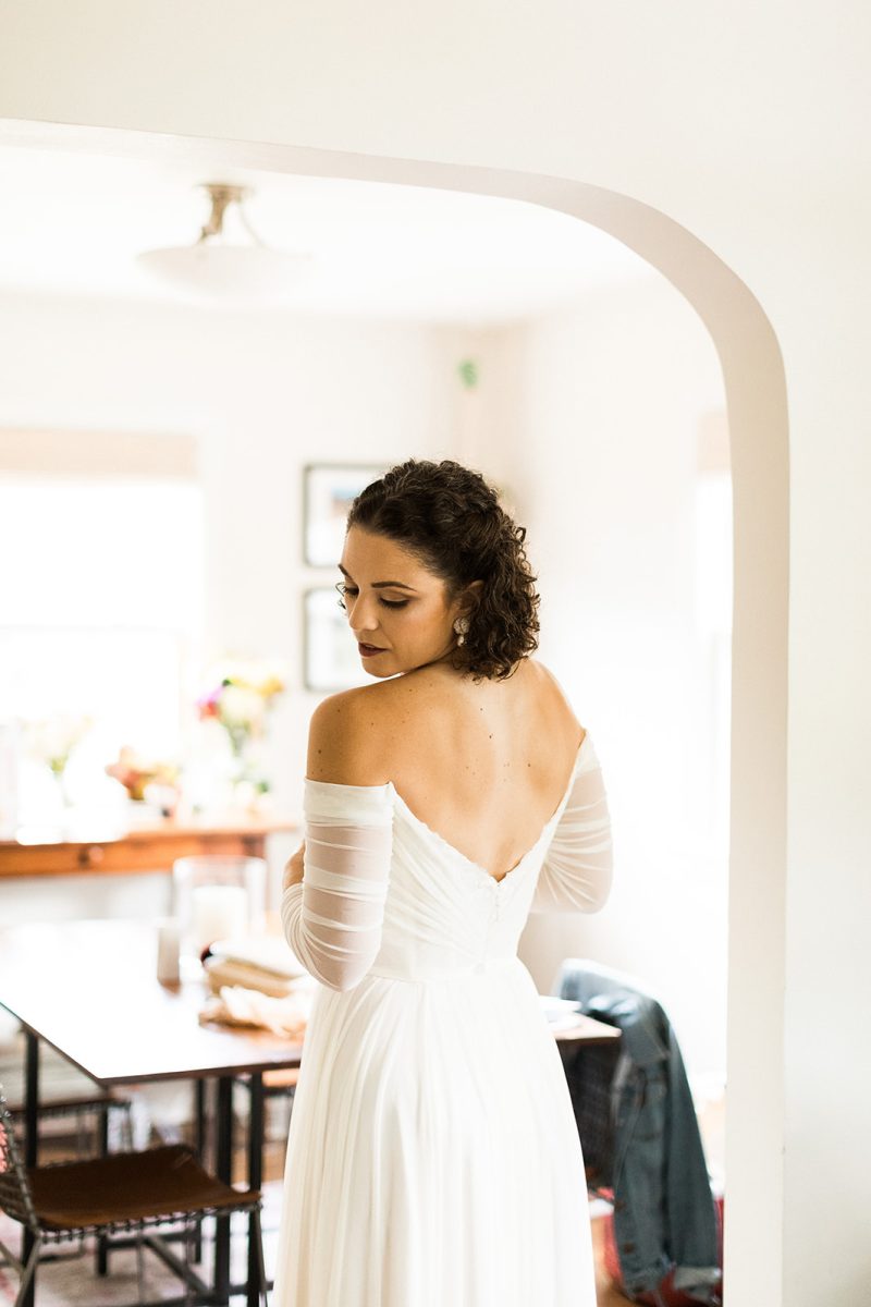 bride with short curly hair wearing off-the-shoulder wedding gown