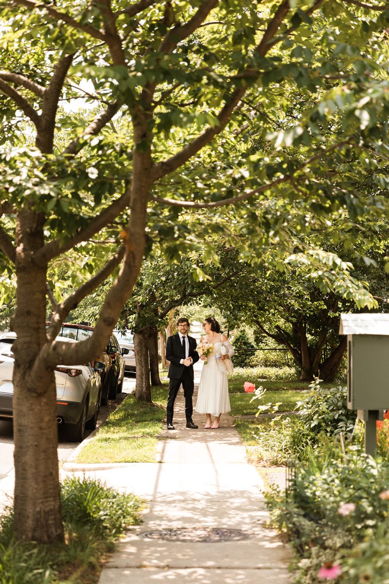 Bride and groom walking on the sidewalk in their neighborhood in old town alexandria