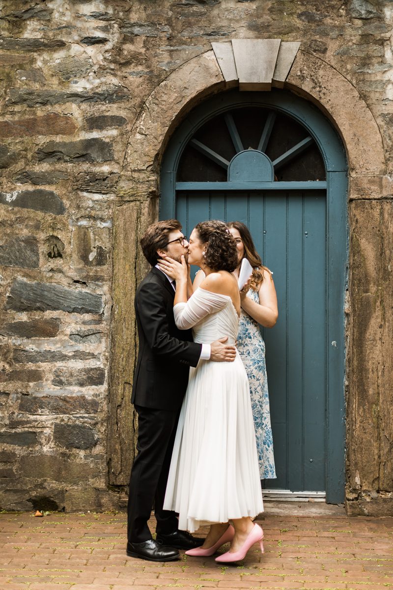 bride and groom first kiss in front of blue arched door at carlyle house