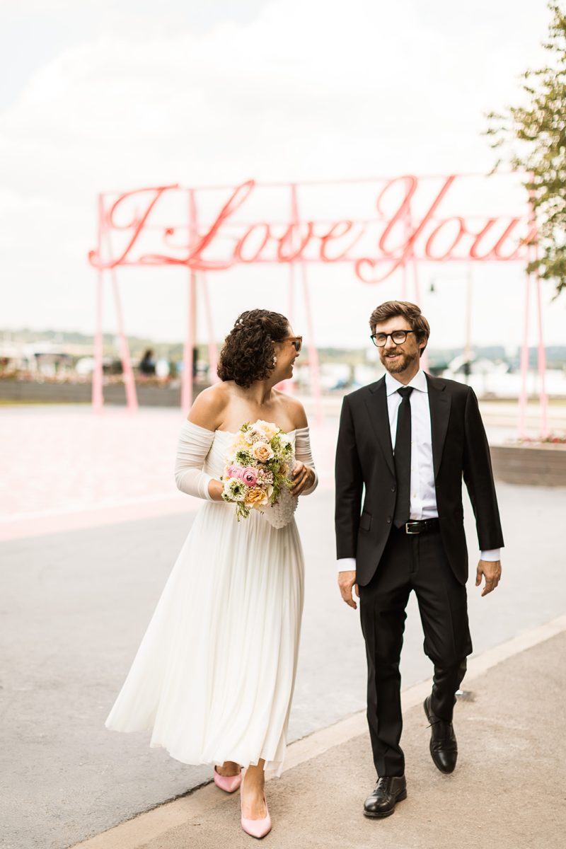 bride and groom walking away from the "I love you" sign in old town alexandria