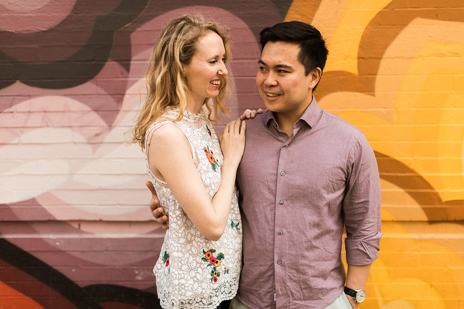 Couple with arms around each other in front of colorful mural in NYC