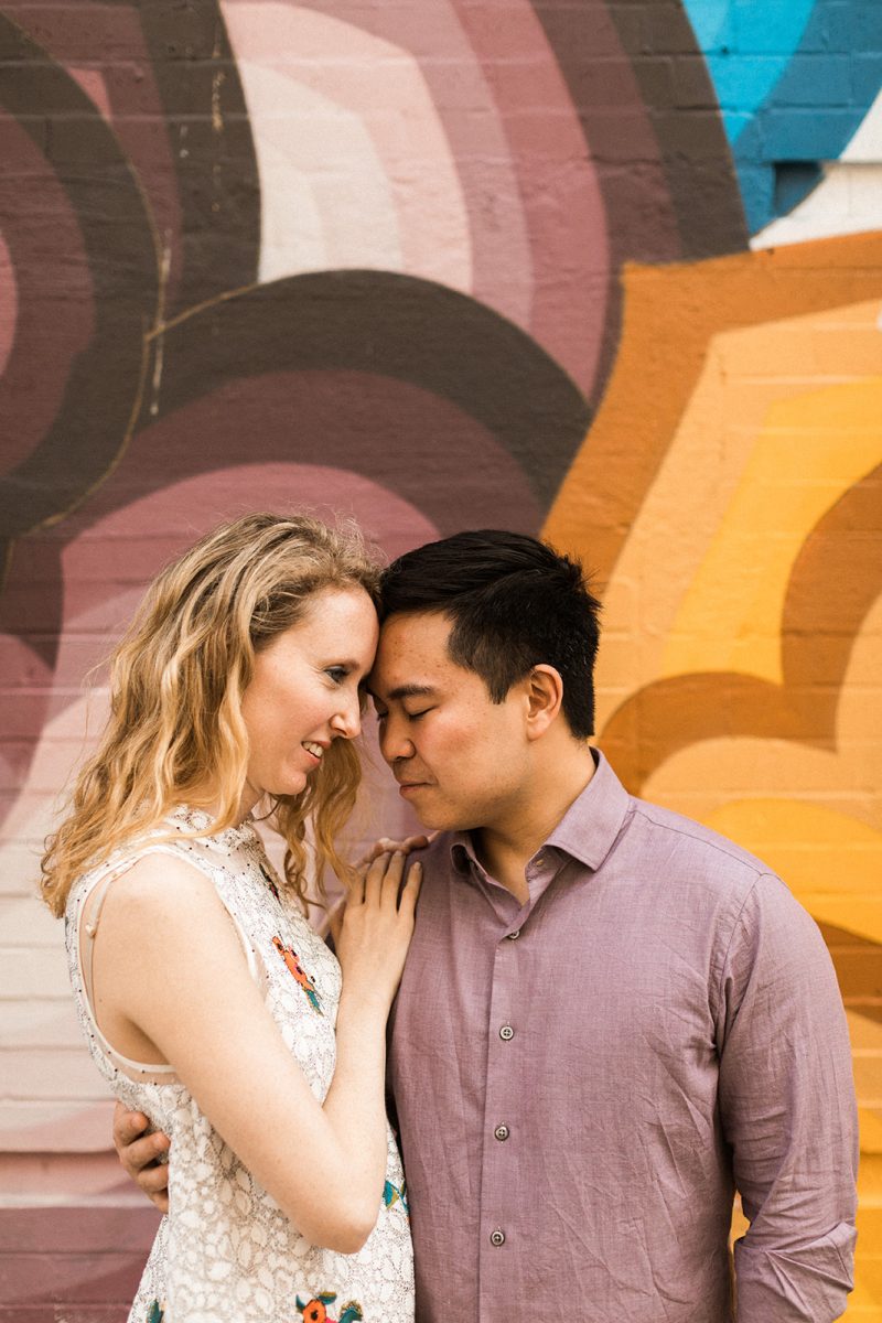 man and woman embracing in front of colorful mural in soho