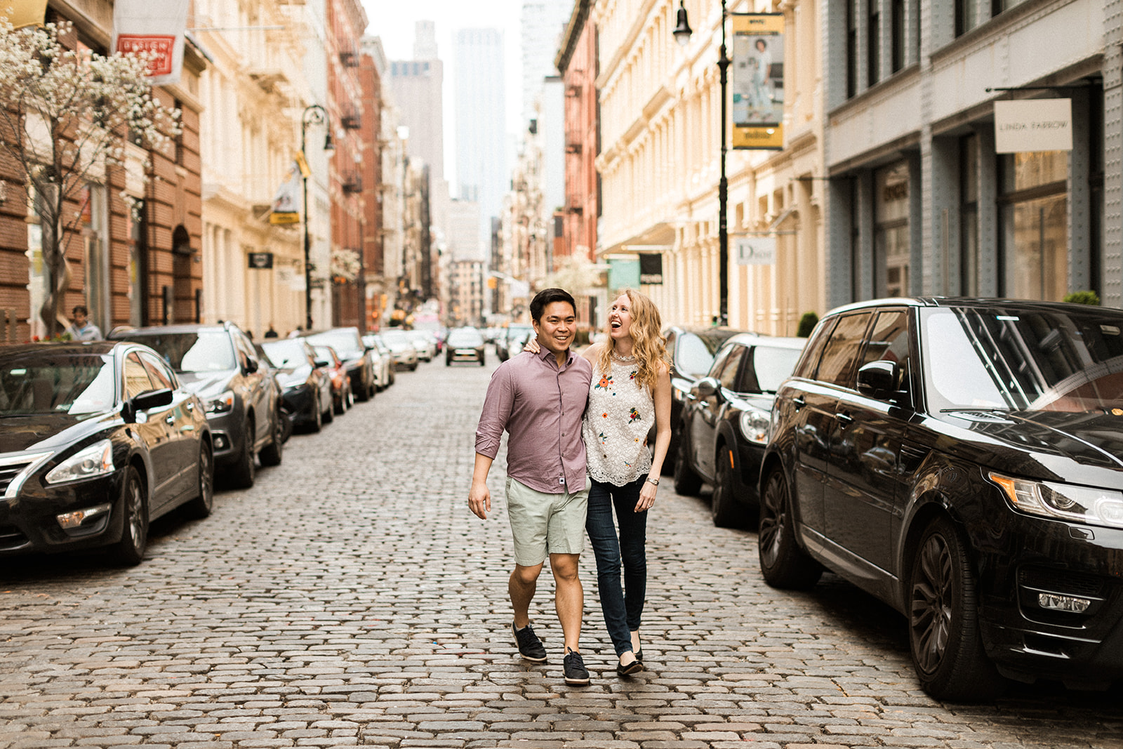 couple walking down cobblestone streets in nyc with arms around each other