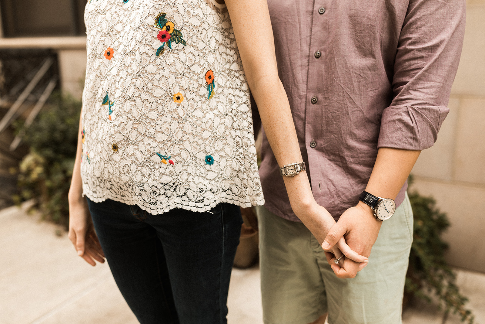 man and woman holding hands showing watches and engagement ring 