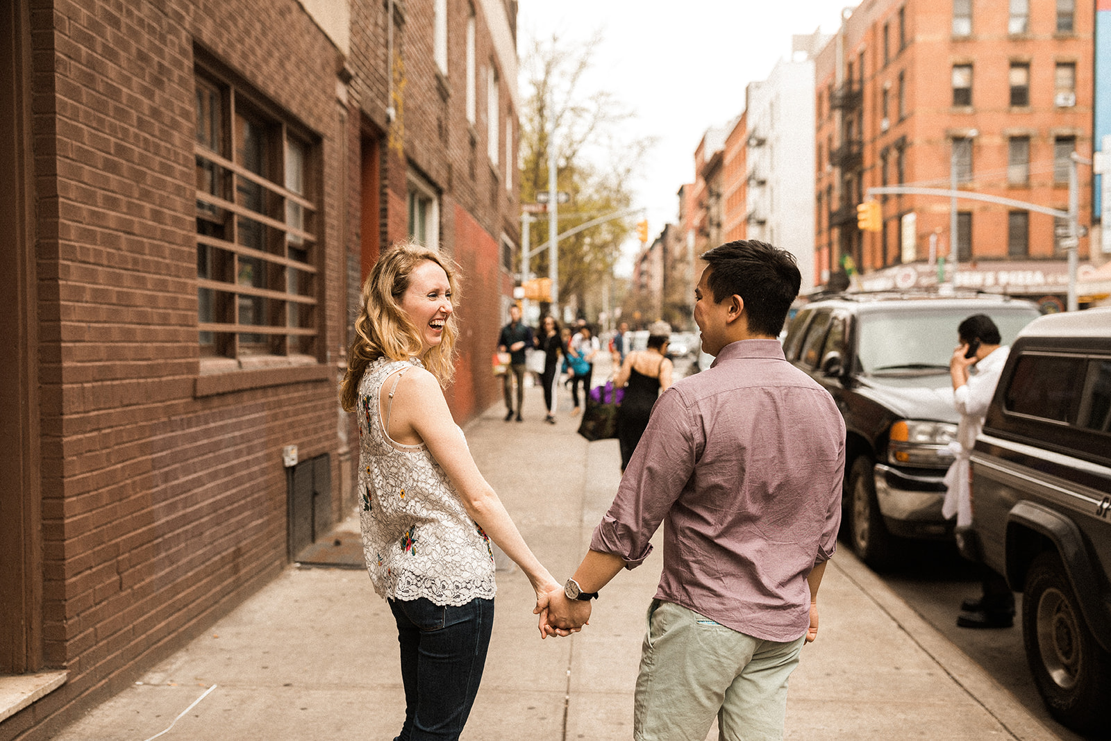 couple holding hands and laughing on sidewalk in nyc 