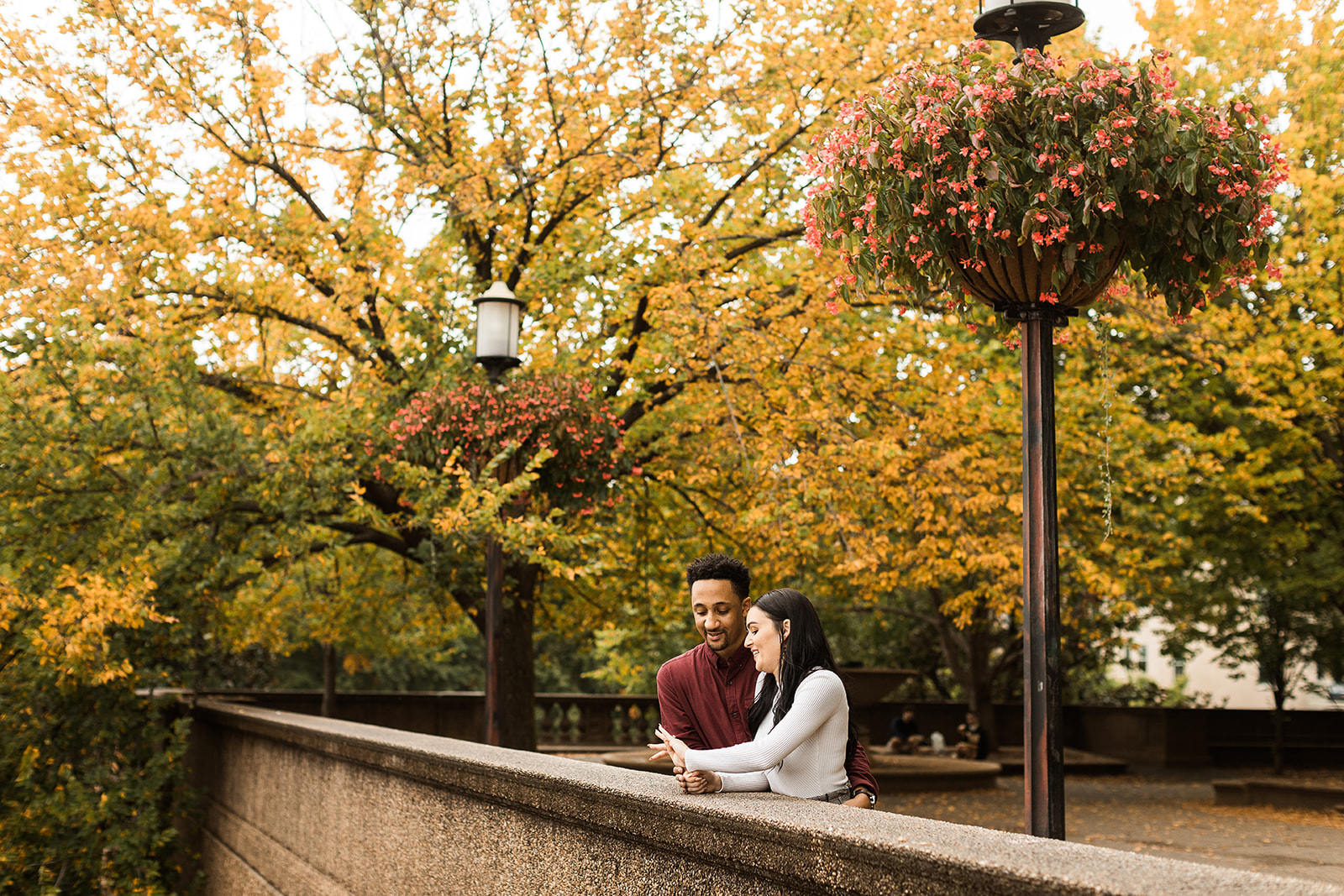 man and woman leaning on railing admiring engagement ring 