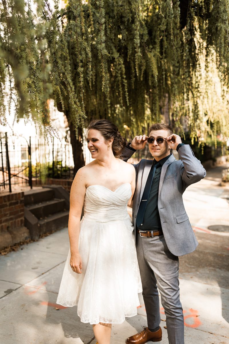bride wearing tea length dress and groom wearing grey suit with sunglasses