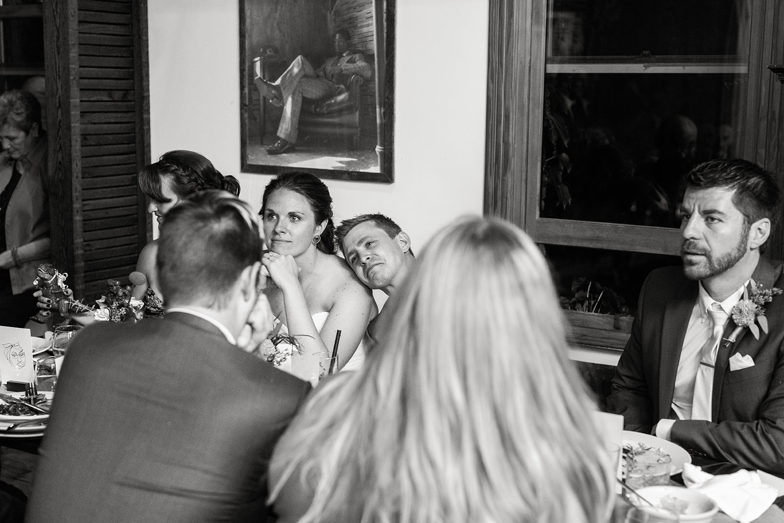 bride and groom listening to speeches at wedding reception 